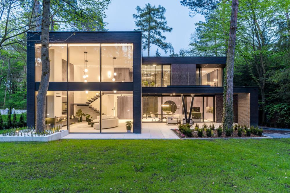 Modern glass-fronted villa surrounded by trees